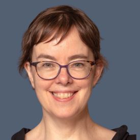 Headshot of smiling brunette woman with short hair and glasses